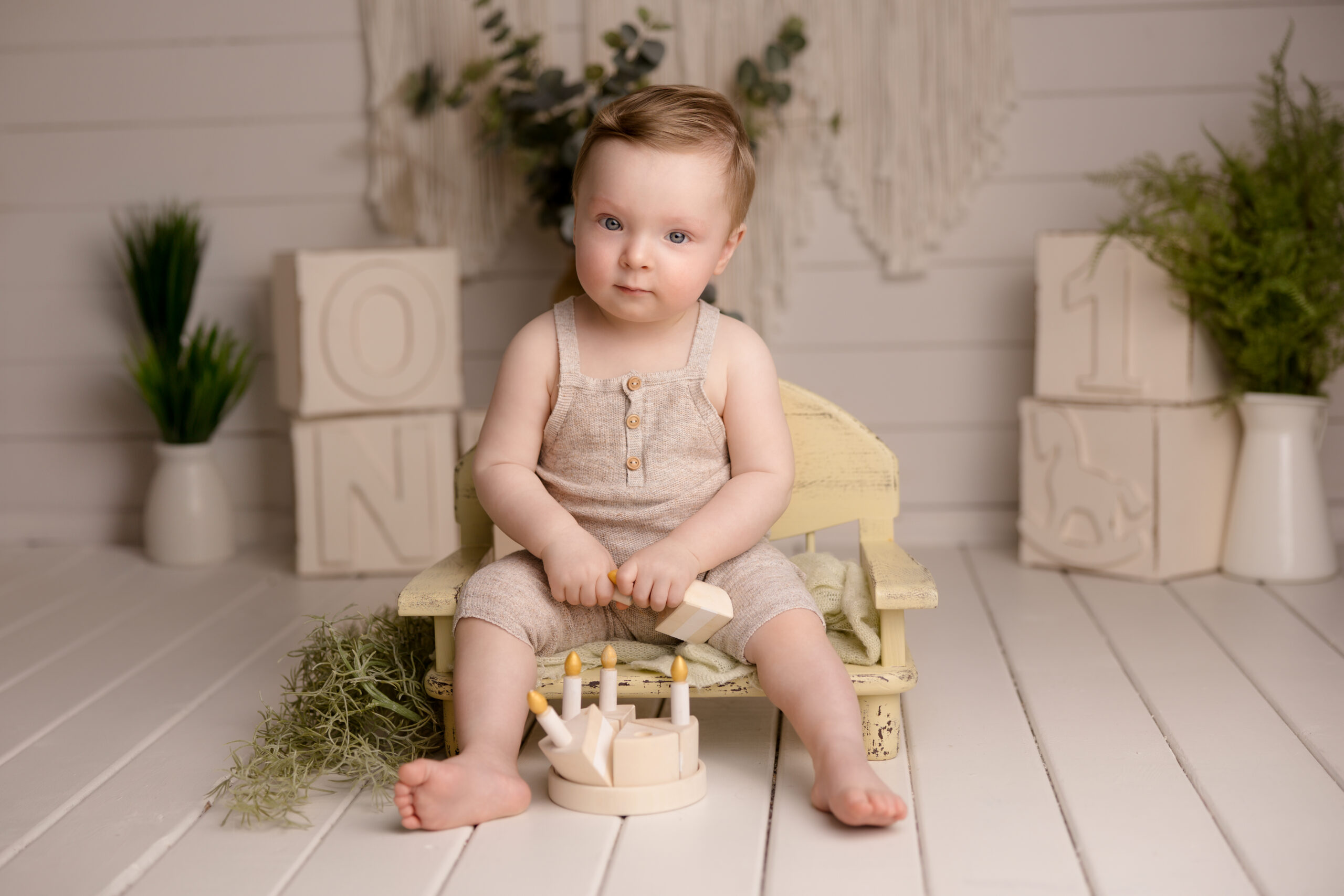 Cake Smash at Wimbledon clapham and Fulham little boy sits next to a wooden cake London Studio first birthday photoshoot SW19